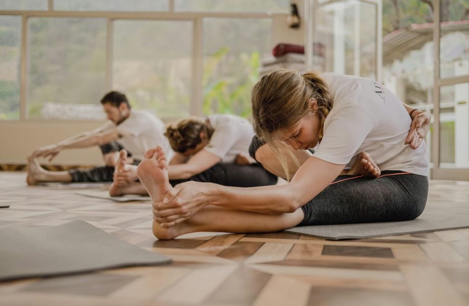 Adults practicing yoga stretches on studio floor, supporting flexibility and active wellness with hemp-derived products