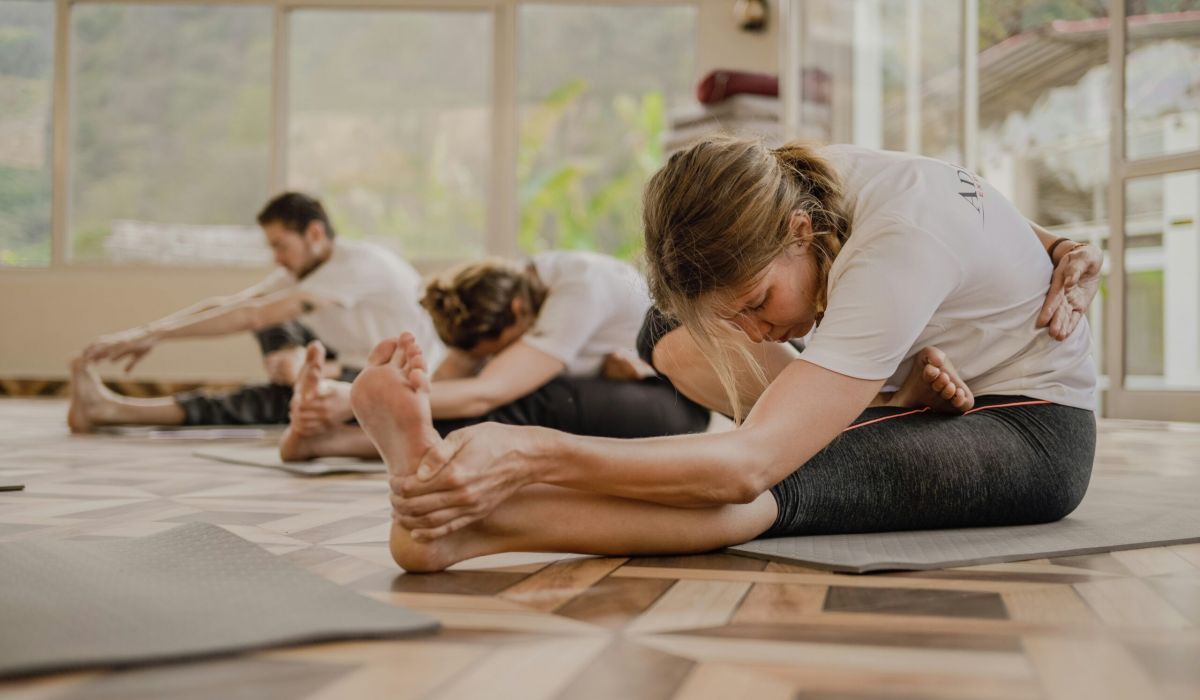 Adults practicing yoga stretches on studio floor, supporting flexibility and active wellness with hemp-derived products